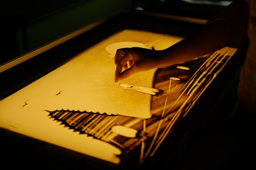 Close-up of hands gently shaping a colorful mandala sand art, symbolizing mindfulness.