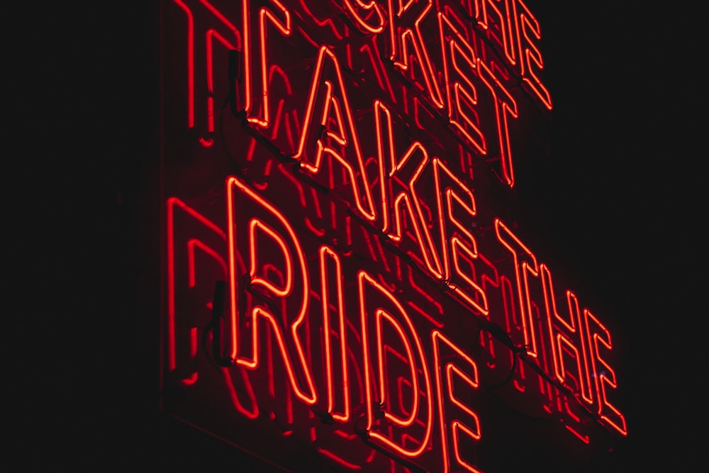 a red neon sign that says it's okay to take the ride