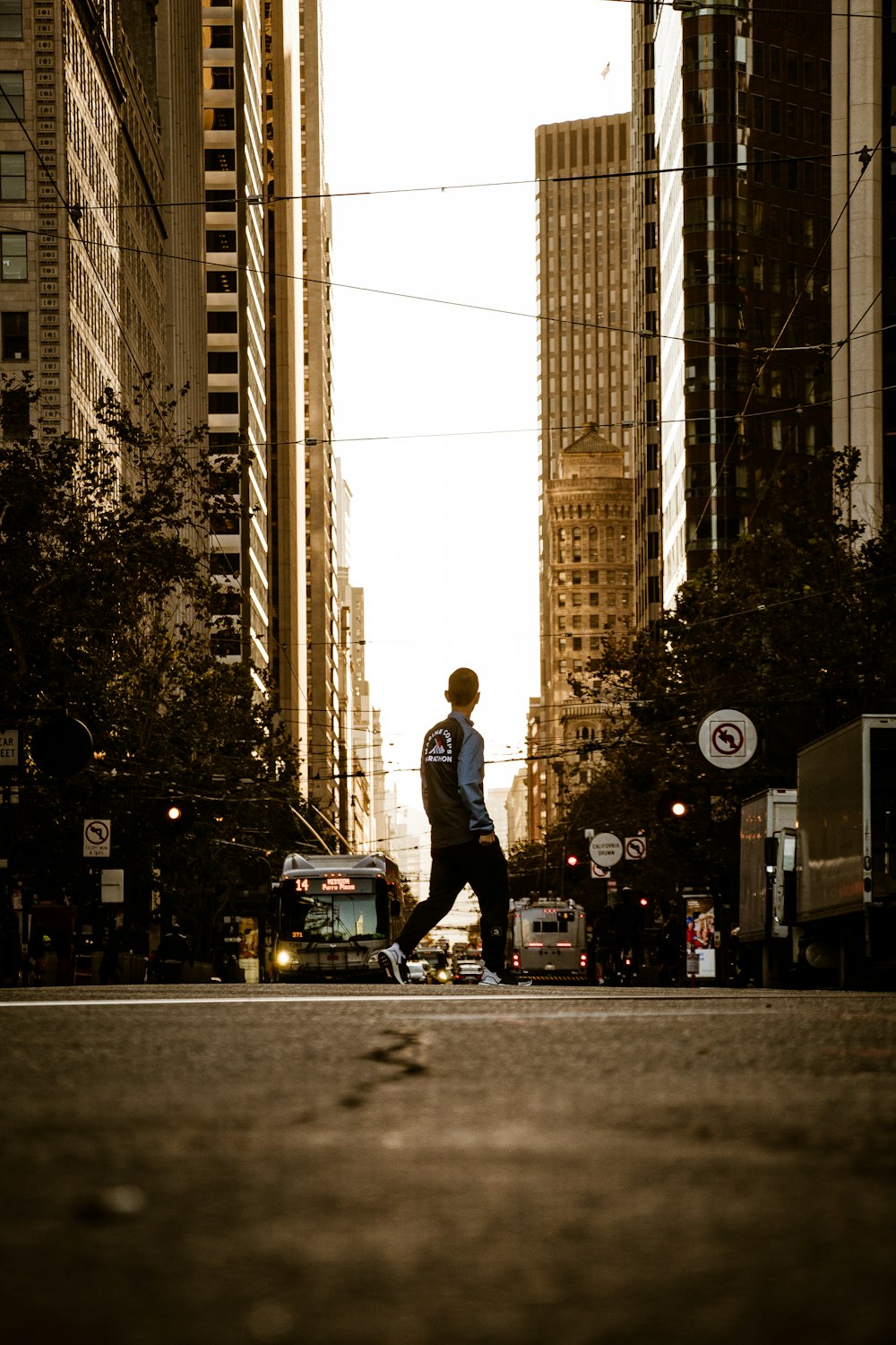 man walking in the middle of the road of the city during day