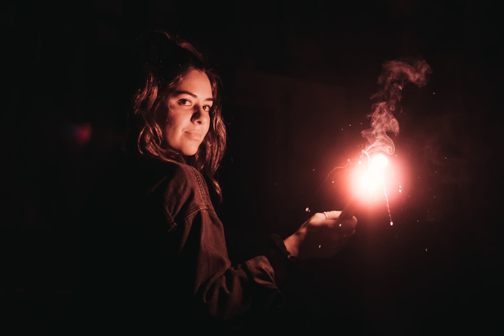woman wearing black jacket standing while holding sparklers