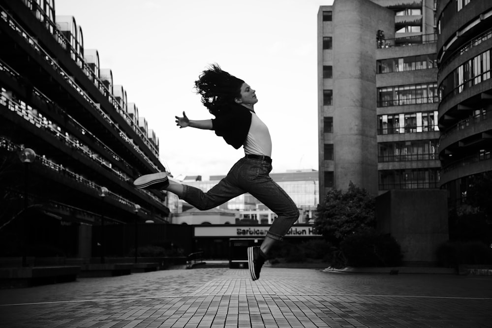 Mujer salta en fotografía en escala de grises