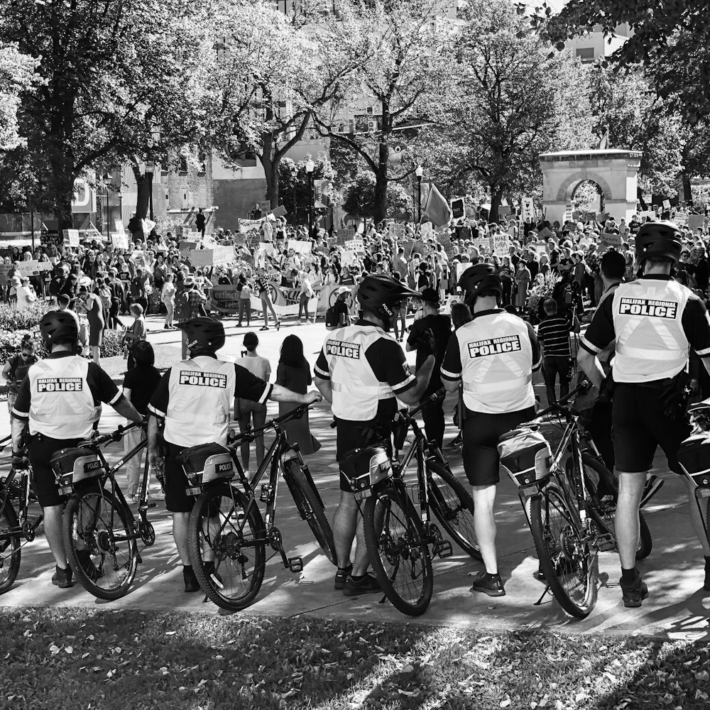 grayscale photo of policemen beside bikes