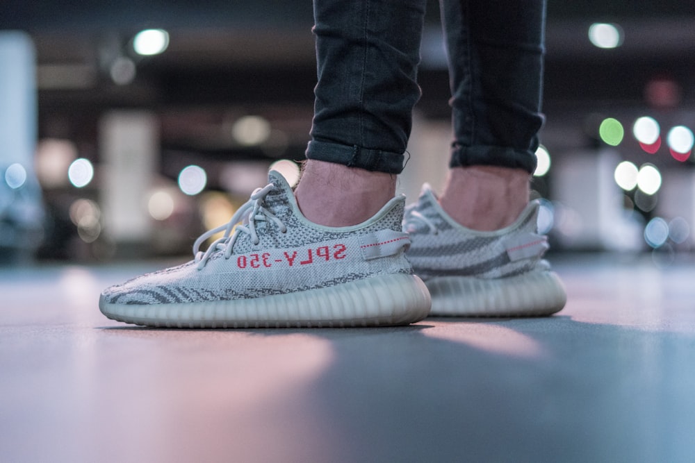 회색 adidas Yeezy Boost V2 신발을 신고 있는 사람