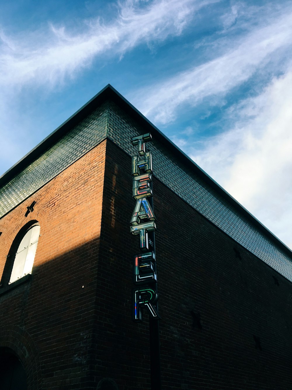 brown Theater building under white and blue sky during daytime