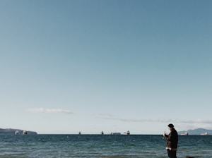 A fleet manager checking live GPS data on a smartphone with boats and trucks in the background.