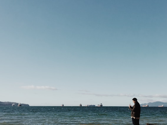 A fleet manager checking live GPS data on a smartphone with boats and trucks in the background.