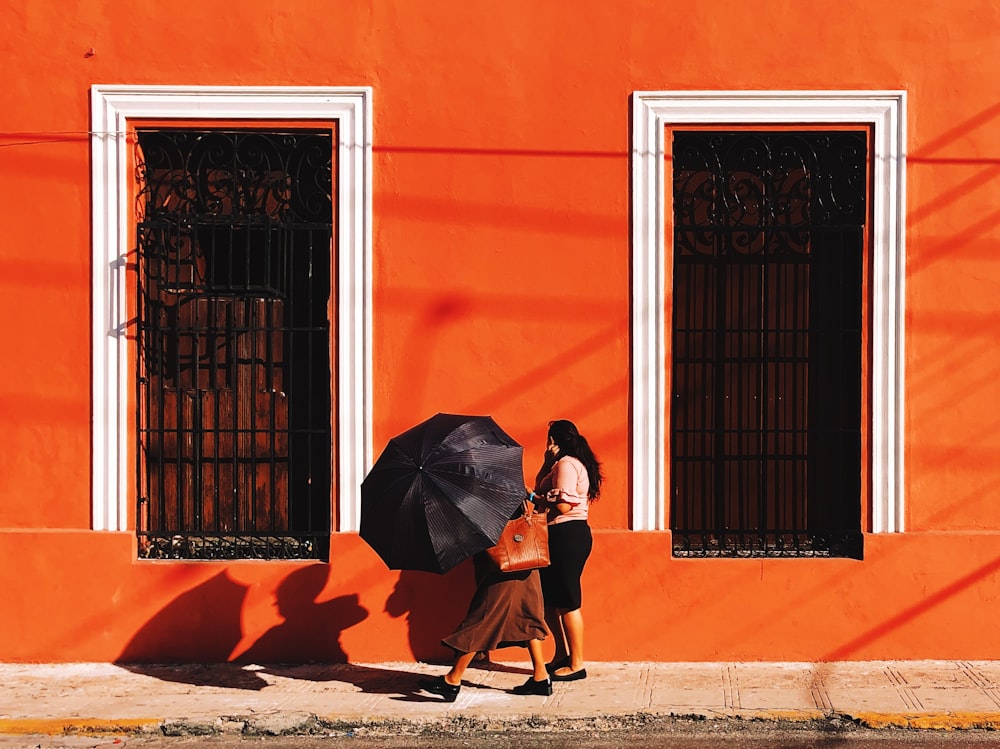 two women walking on pathway near building during daytime