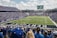 A large football stadium filled with fans watching a live game. Players are on the field, and the atmosphere is lively with a full audience. The scoreboard displays the action, and banners for the Kentucky Wildcats are visible.