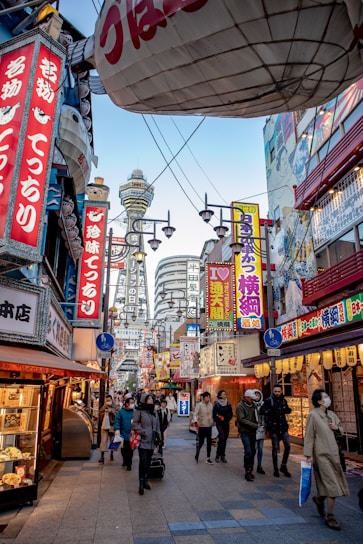 A vibrant street scene in Tokyo with colorful signs and bustling crowds under cherry blossoms.
