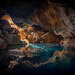 cave surrounded with blue body of water