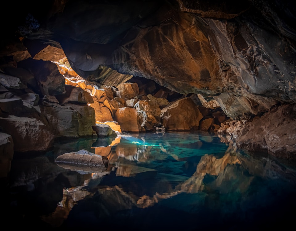 cave surrounded with blue body of water