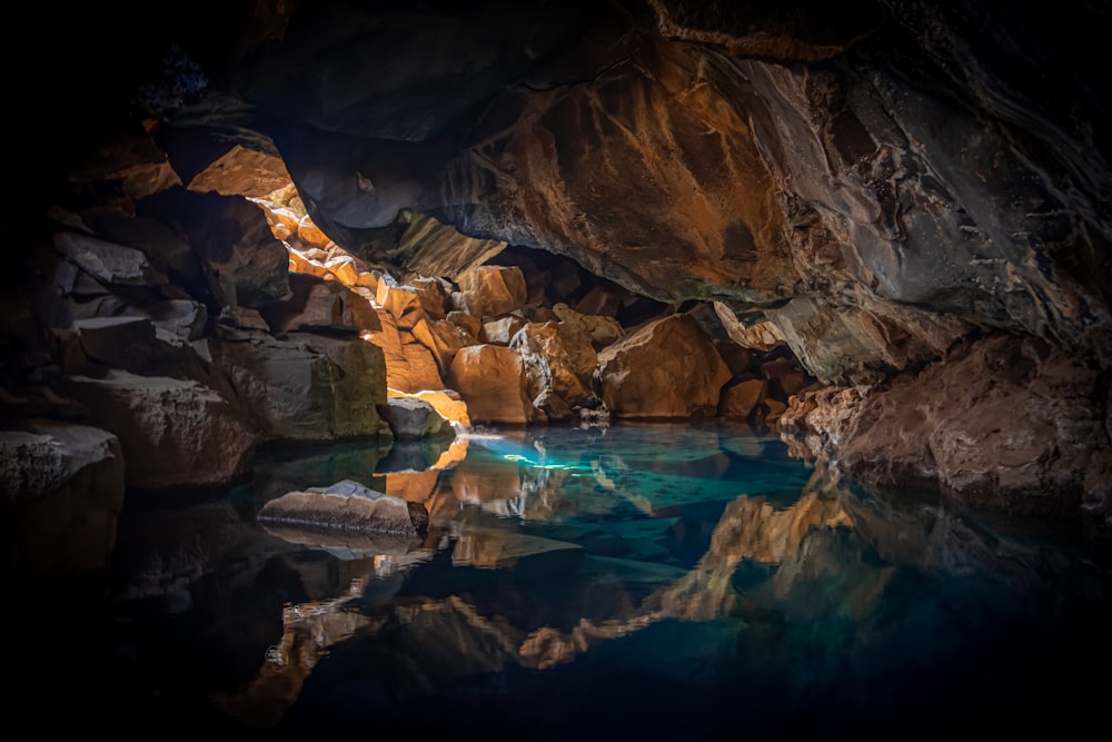cave surrounded with blue body of water