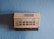 A vintage Honeywell thermostat is mounted on a textured light blue wall. The thermostat features a beige color with numerous buttons for programming and setting temperatures, along with a small display screen.