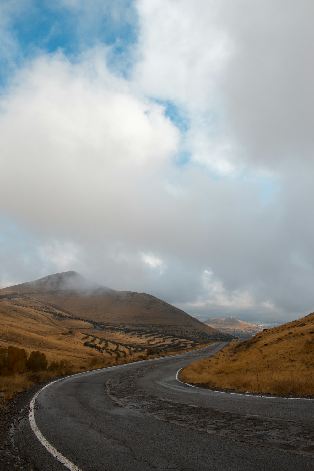 asphalt roadway beside mountain during daytime