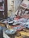 A fish market display features a variety of fresh seafood arranged on wooden tables. Baskets hold small fish, while large cuts of fish meat and whole fish are laid out neatly. The rustic setting includes tiled walls and weathered doors.