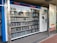 A vending machine filled with neatly arranged books is situated outdoors. There is a digital display above the machine showing text in a language that appears to be Chinese. Next to the machine is a panel with information and instructions, possibly related to how to operate it.