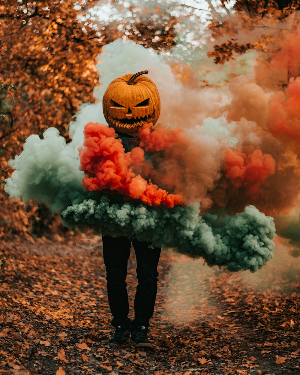 person wearing pumpkin mask covered with multi-colored smoke