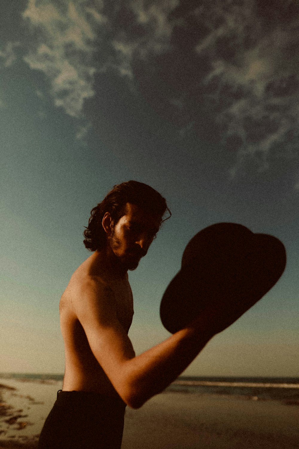 man holding hat while on seashore