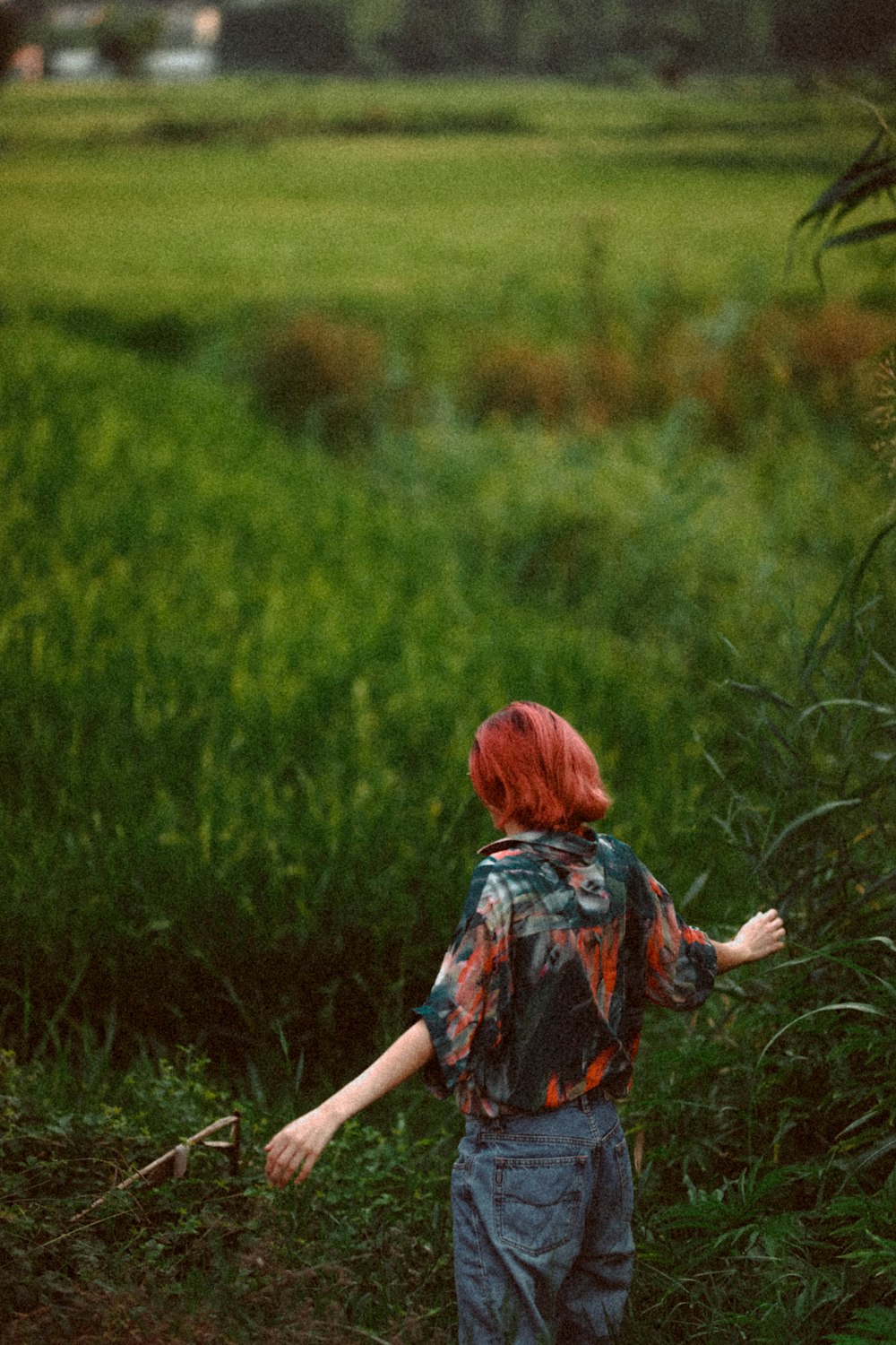 woman with red hair by a green field