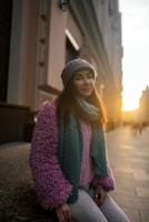 A cozy scene with a model wearing a stylish jacket and scarf, standing in a sunlit urban street