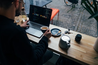 A friendly web designer working on a laptop in a cozy Melbourne cafe, with plumbing tools and coffee cups nearby.