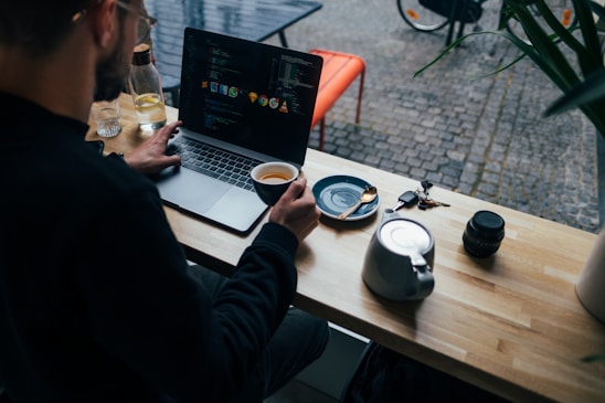 A friendly web designer working on a laptop in a cozy Melbourne cafe, with plumbing tools and coffee cups nearby.