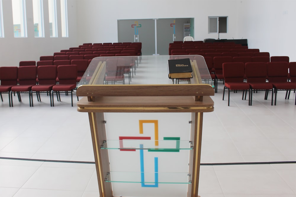 bible on clear glass lectern in front of empty red chairs