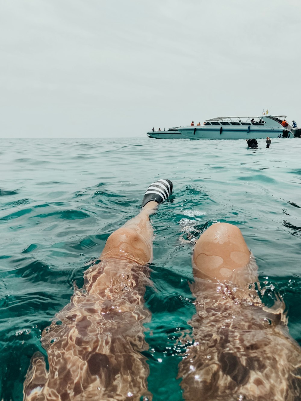 person swims near yacht