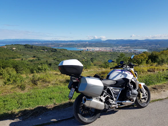 A motorcyclist using the puncture repair kit on a roadside with a scenic green landscape.
