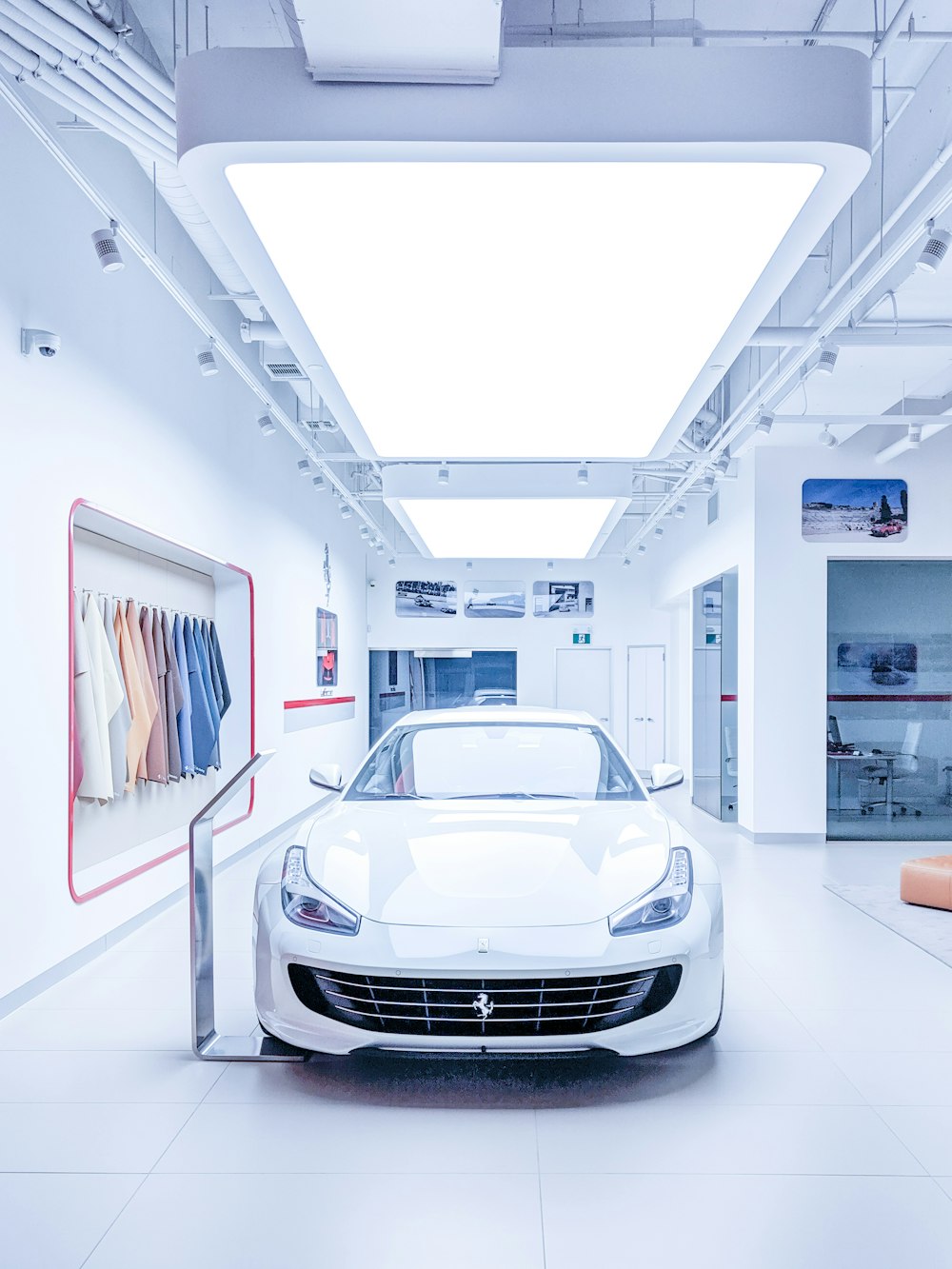 white Ferrari inside white building with hanged clothes