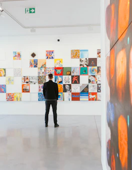 man in black long-sleeved shirt and black bottoms standing behind abstract paintings