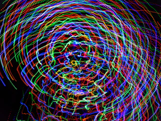 A mesmerizing swirl of colorful spinning light sticks forming dynamic shapes.