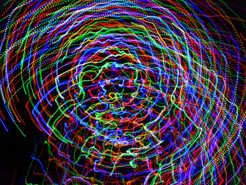 A mesmerizing swirl of colorful spinning light sticks forming dynamic shapes.