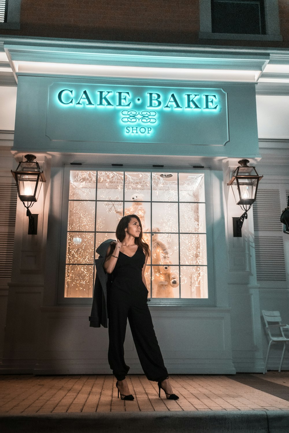 밤에 케이크 베이크 가게 앞에 서 있는 여자