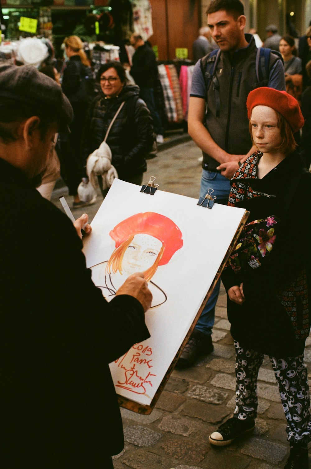 standing man painting standing girl wearing red hat during daytime