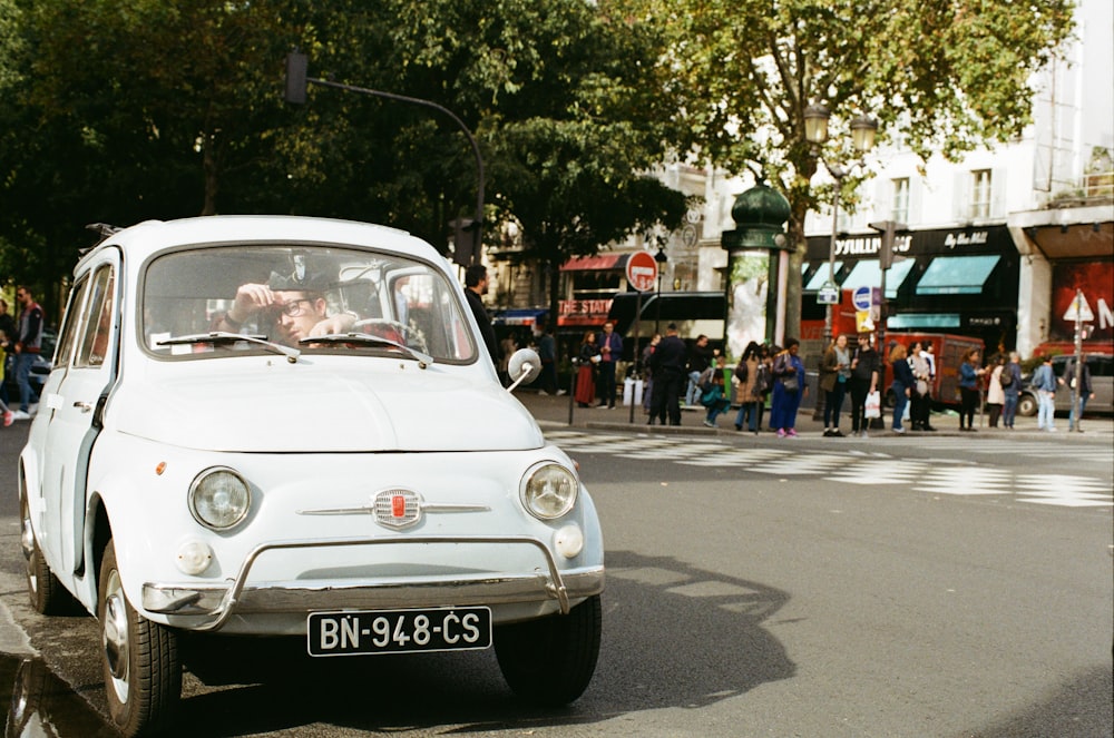 vintage white vehicle parked beside curb during daytime