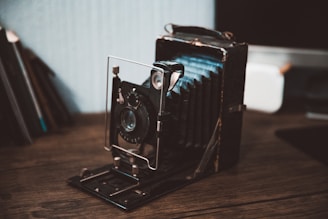 A vintage stereoscopic camera from the late 19th century displayed on a wooden table with old stereoscopic cards scattered around.