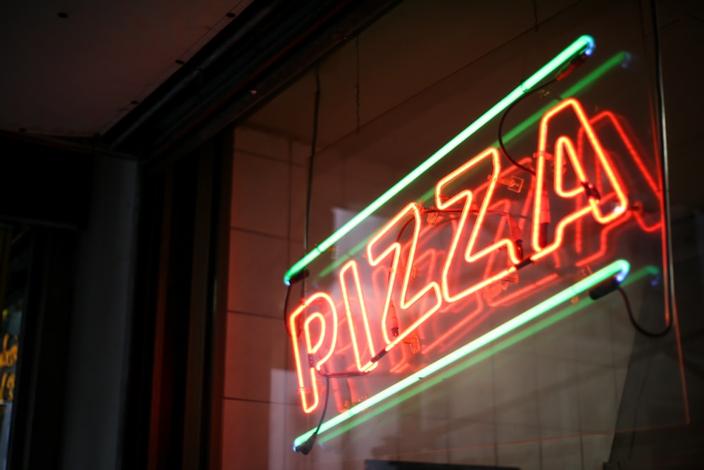 Photo de mise au point peu profonde de la signalisation lumineuse au néon de pizza éclairée