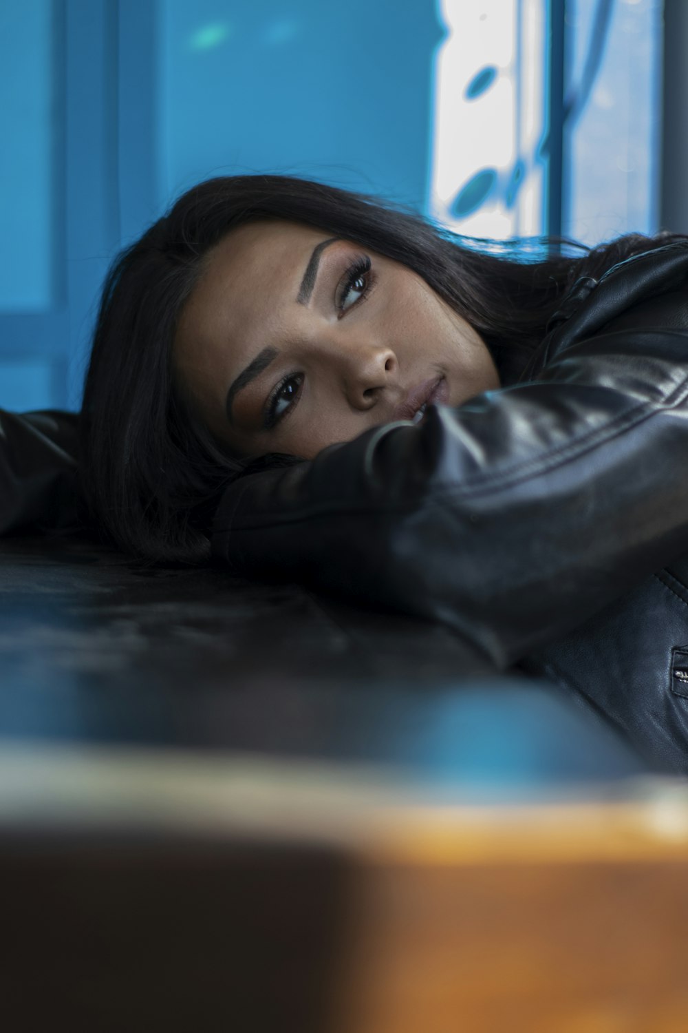 woman wears black leather jacket and leans on table