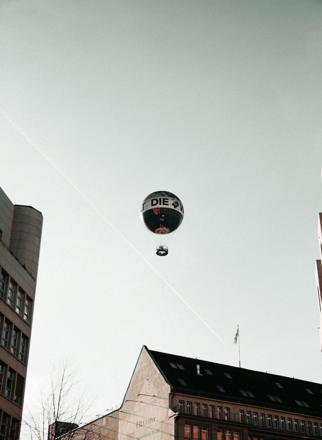 low-angle photography of white and black hot-air balloon over white concrete building