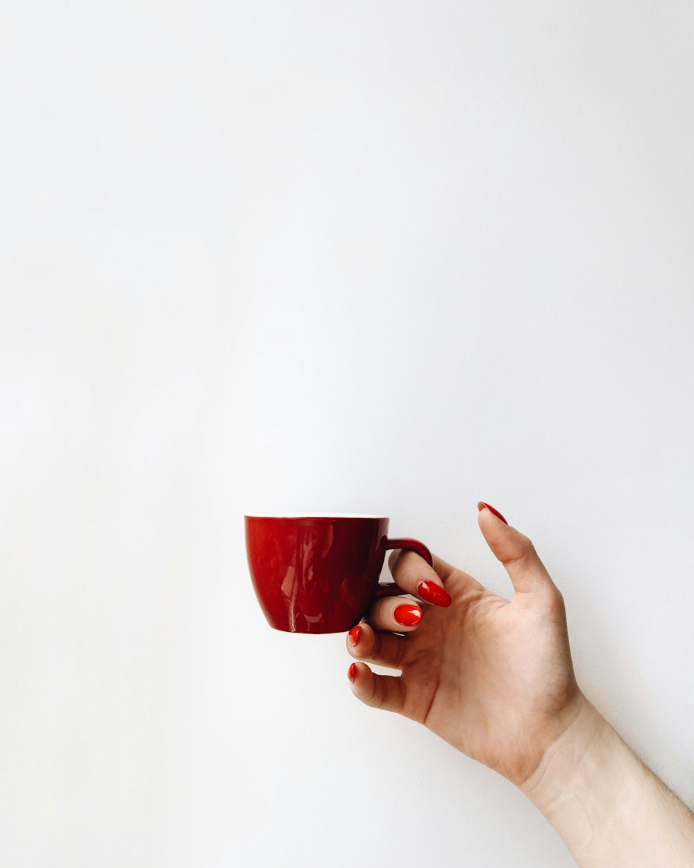 woman with red manicure holds red cup