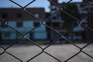 Workers installing a chain-link fence on a sunny day