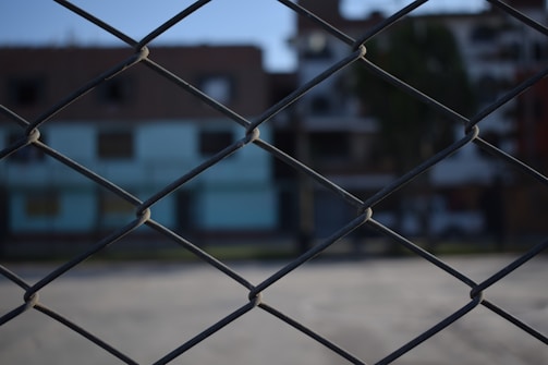 Close-up of black privacy tape woven tightly into chain link fence under bright sunlight