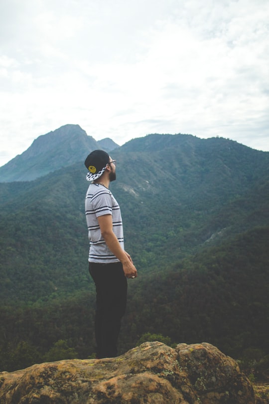 man in gray and red striped shirt standing while facing mountains in Cerro La Campana Chile