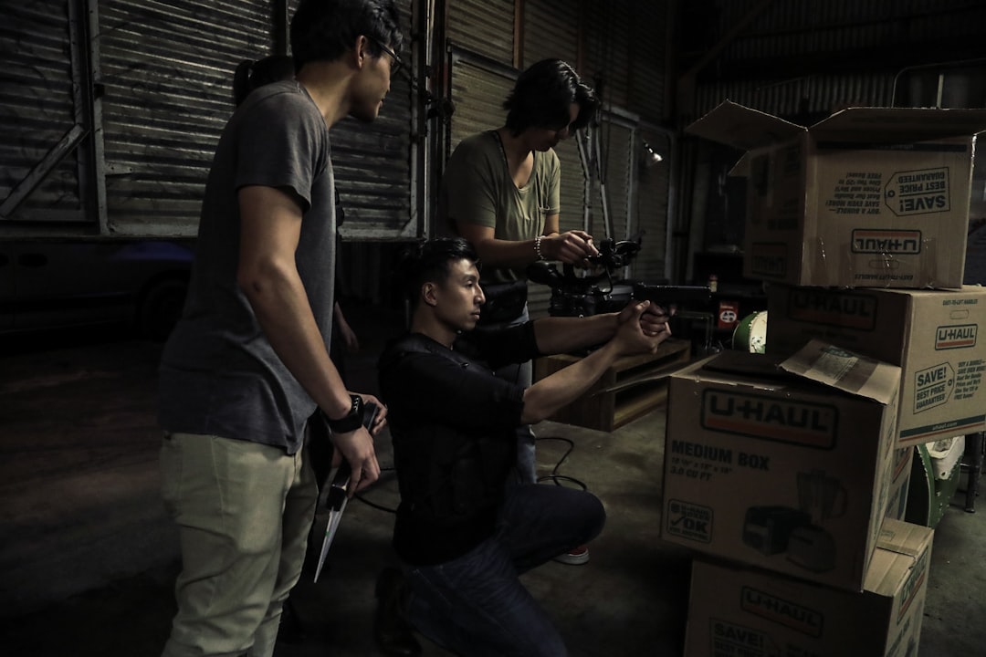 two man standing in front of man sitting in front of box inside building