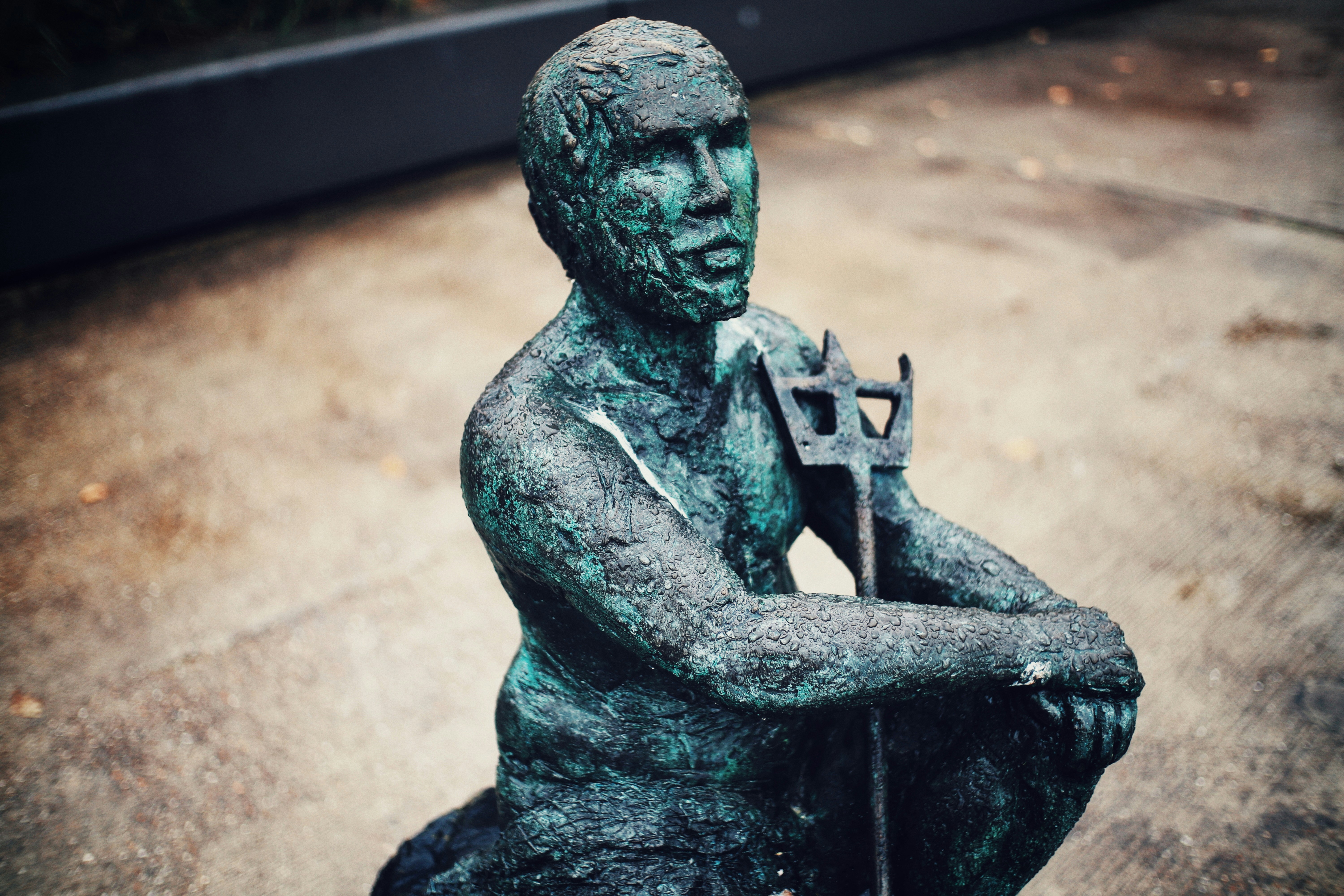Statue eines Mannes, der in der Nähe einer grauen Oberfläche sitzt