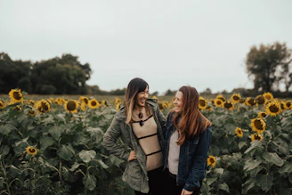 two women standing in front of sunflower field