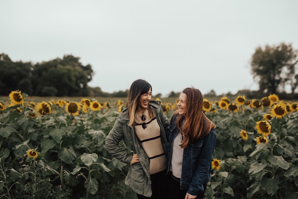 two women standing in front of sunflower field