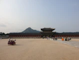 A panoramic view of a restored palace courtyard bustling with visitors.