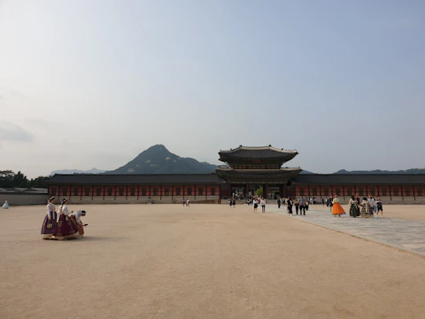 A panoramic view of a restored palace courtyard bustling with visitors.